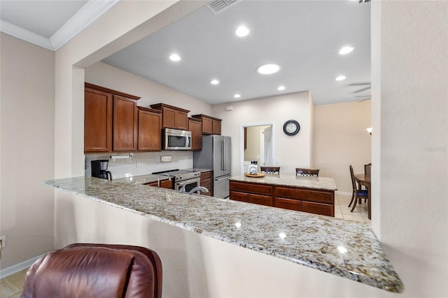 kitchen featuring kitchen peninsula, appliances with stainless steel finishes, light stone counters, and crown molding