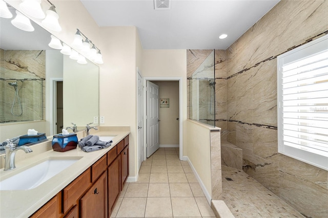 bathroom with tile patterned flooring, vanity, and a tile shower