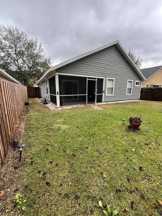 rear view of property featuring a sunroom and a lawn