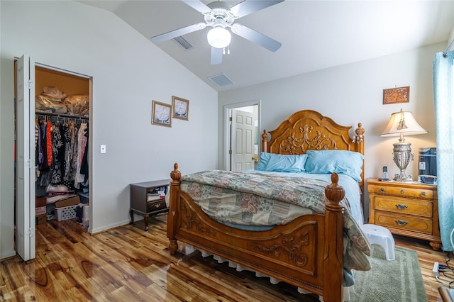 bedroom featuring ceiling fan, hardwood / wood-style floors, lofted ceiling, a walk in closet, and a closet