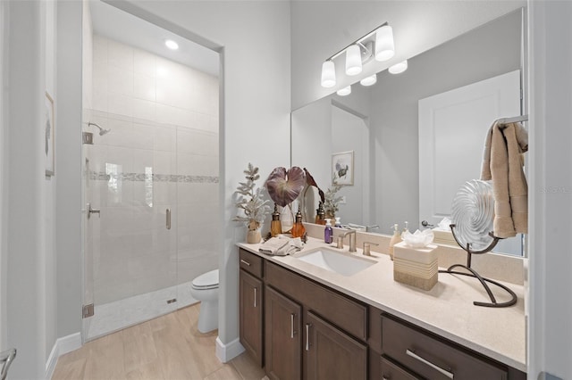 bathroom featuring hardwood / wood-style flooring, a shower with door, vanity, and toilet