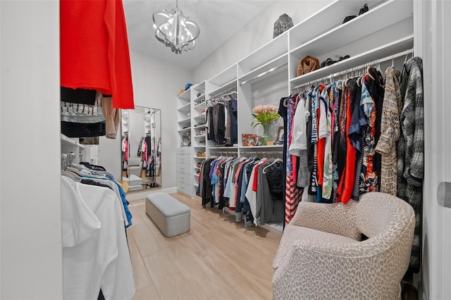 spacious closet with hardwood / wood-style floors and an inviting chandelier