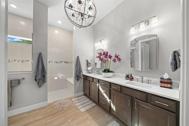 bathroom featuring a tile shower, vanity, wood-type flooring, and an inviting chandelier