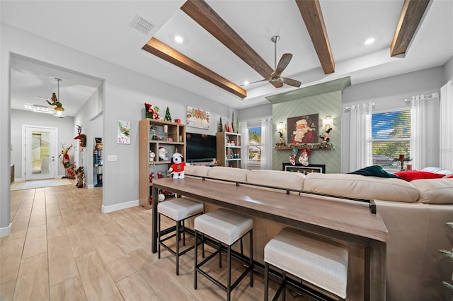 kitchen with a raised ceiling, ceiling fan, a kitchen breakfast bar, and a fireplace