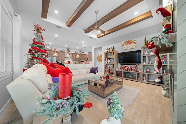 living room with ceiling fan, beam ceiling, light wood-type flooring, and a tray ceiling