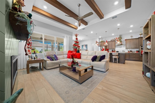 living room featuring ceiling fan, beamed ceiling, and light wood-type flooring