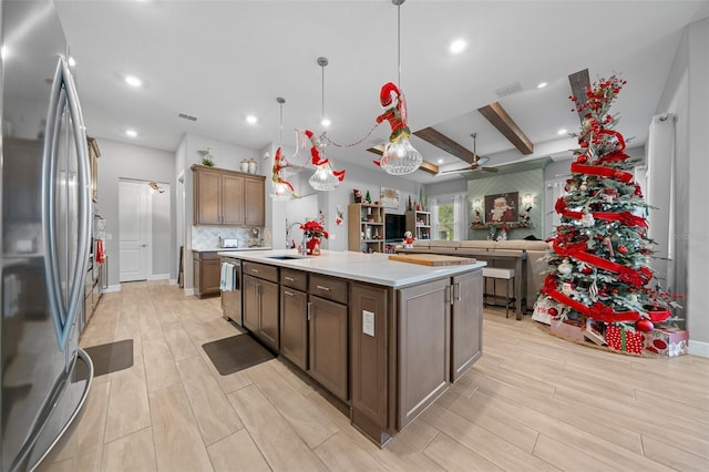 kitchen with a center island with sink, sink, light hardwood / wood-style flooring, decorative light fixtures, and stainless steel appliances