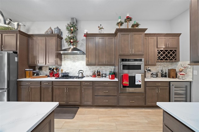 kitchen featuring appliances with stainless steel finishes, wall chimney exhaust hood, beverage cooler, and tasteful backsplash