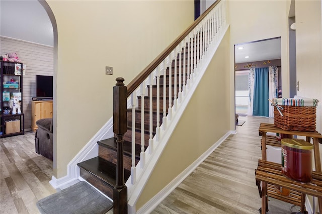 stairway with a towering ceiling, wood-type flooring, and wooden walls