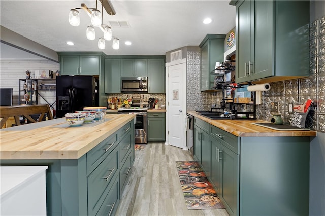 kitchen with appliances with stainless steel finishes, wood counters, and green cabinetry