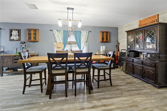 dining room featuring an inviting chandelier, a textured ceiling, and light wood-type flooring