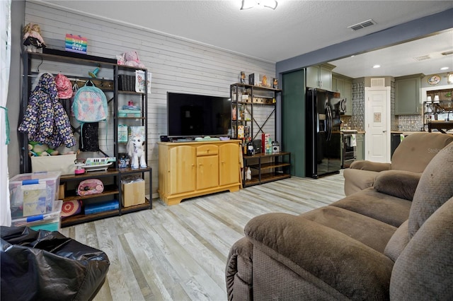 living room featuring bar, a textured ceiling, and light hardwood / wood-style flooring