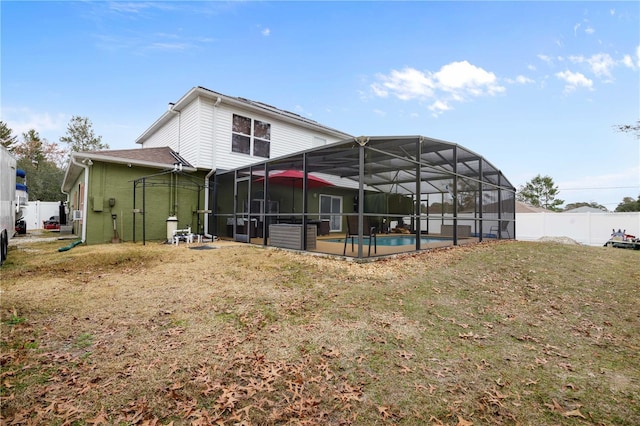 back of property featuring a fenced in pool, glass enclosure, and a lawn