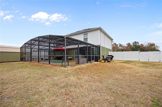 back of house featuring a fenced in pool, glass enclosure, and a lawn