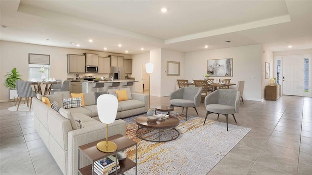 living room with a tray ceiling and light tile patterned flooring