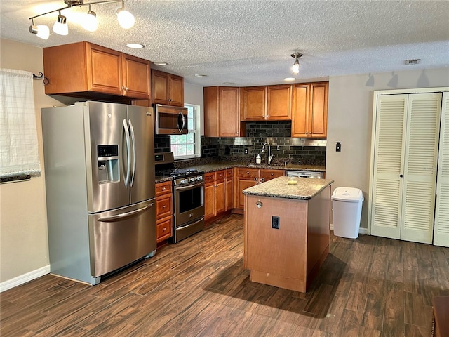 kitchen with appliances with stainless steel finishes, a textured ceiling, sink, a center island, and dark hardwood / wood-style floors