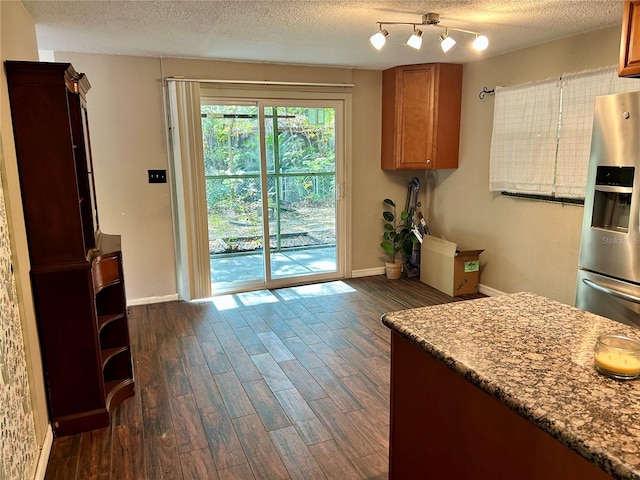 kitchen with stainless steel fridge, dark hardwood / wood-style flooring, a textured ceiling, and light stone counters