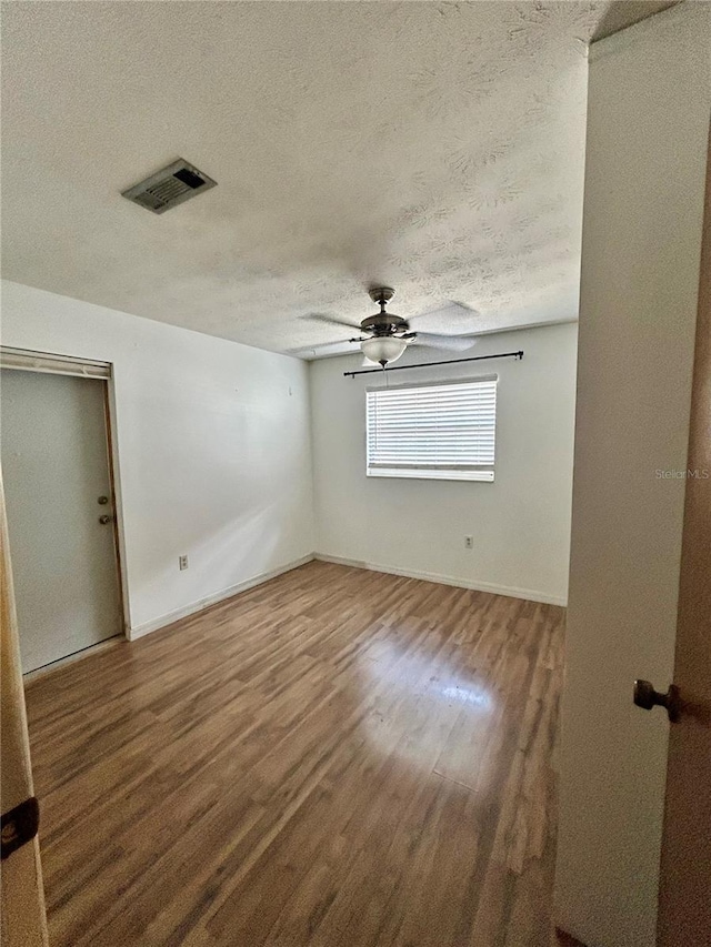 empty room with ceiling fan, a textured ceiling, and hardwood / wood-style flooring