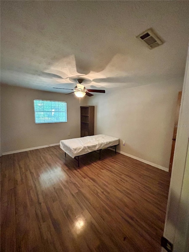 unfurnished bedroom featuring a textured ceiling, ceiling fan, and dark wood-type flooring