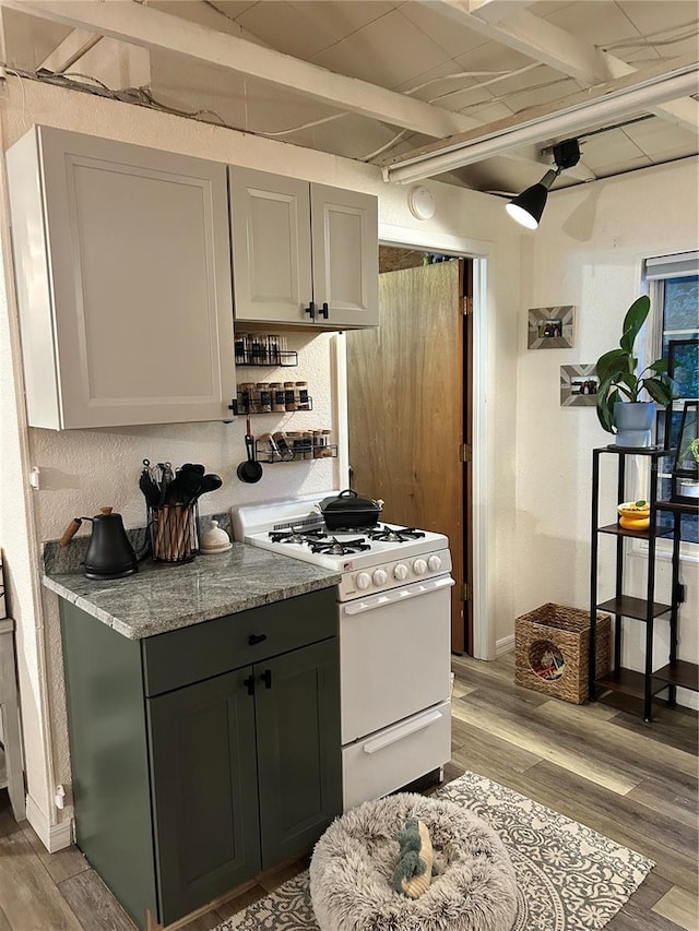 kitchen featuring light wood-type flooring, white gas range oven, light stone counters, ceiling fan, and gray cabinets