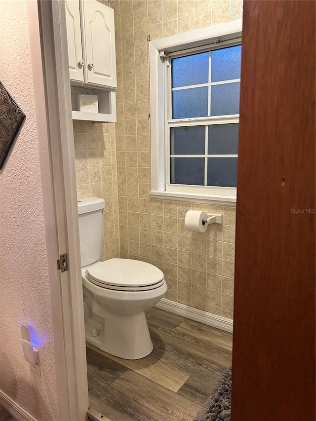 bathroom with hardwood / wood-style flooring, toilet, and tile walls