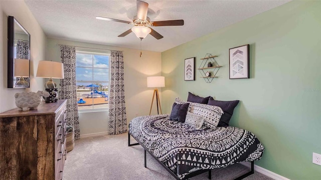 bedroom featuring a textured ceiling, ceiling fan, and light carpet