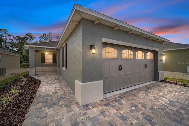 property exterior at dusk featuring central AC and a garage