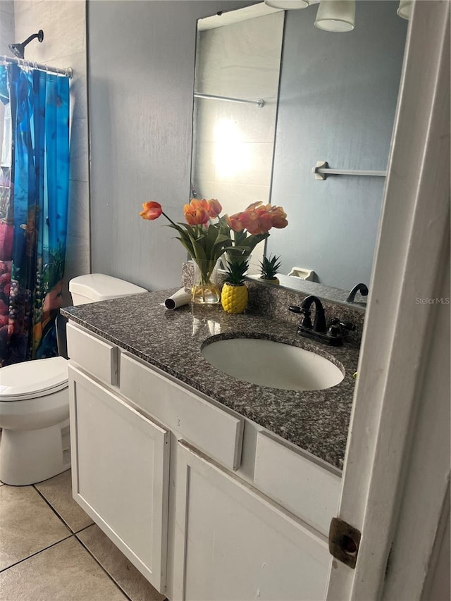 bathroom with toilet, vanity, tile patterned floors, and walk in shower