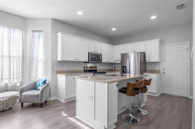 kitchen with a kitchen island with sink, white cabinetry, and stainless steel appliances