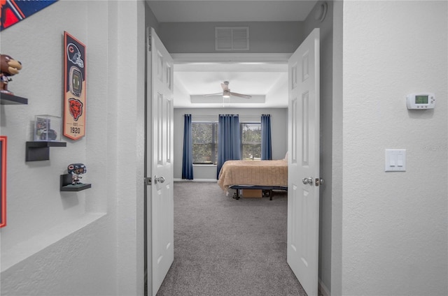 corridor with carpet flooring and a raised ceiling