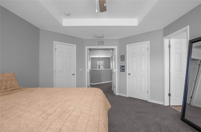 bedroom with dark colored carpet, ceiling fan, and a raised ceiling