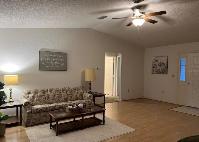 living room featuring ceiling fan, vaulted ceiling, a textured ceiling, and hardwood / wood-style flooring