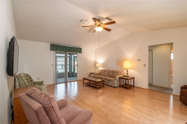 living room with ceiling fan, a textured ceiling, light hardwood / wood-style flooring, and lofted ceiling