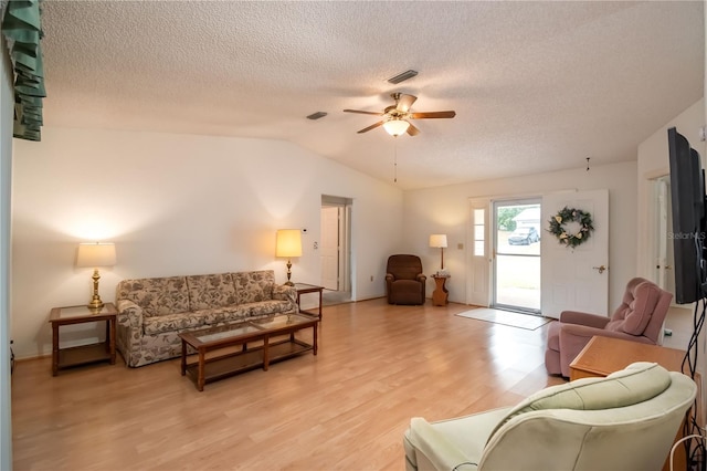 living room with ceiling fan, light wood-type flooring, vaulted ceiling, and a textured ceiling