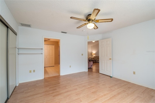 unfurnished bedroom with a textured ceiling, ceiling fan, a closet, and light hardwood / wood-style flooring