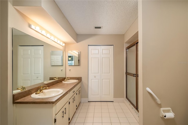 bathroom with walk in shower, vanity, tile patterned floors, and a textured ceiling