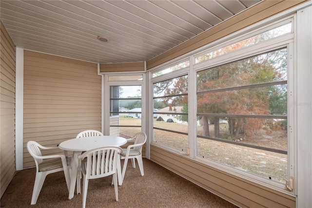 sunroom featuring a water view, a healthy amount of sunlight, and wood ceiling