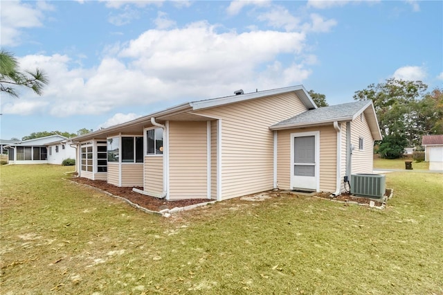 rear view of property featuring a yard and central air condition unit