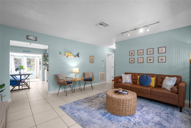 living room with french doors, light tile patterned floors, and a textured ceiling