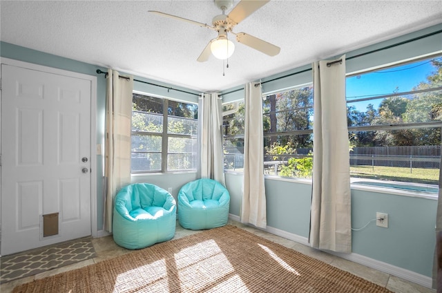 unfurnished sunroom featuring ceiling fan and a healthy amount of sunlight