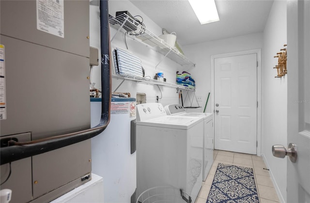 clothes washing area with washer and clothes dryer, light tile patterned floors, and heating unit