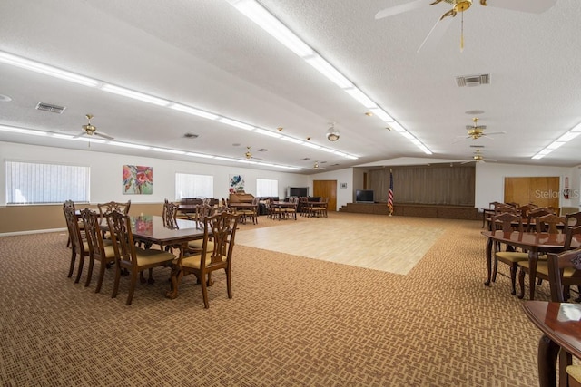 carpeted dining area with ceiling fan, a textured ceiling, and vaulted ceiling