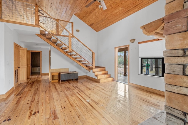 unfurnished living room featuring a towering ceiling, light hardwood / wood-style flooring, ceiling fan, and wood ceiling