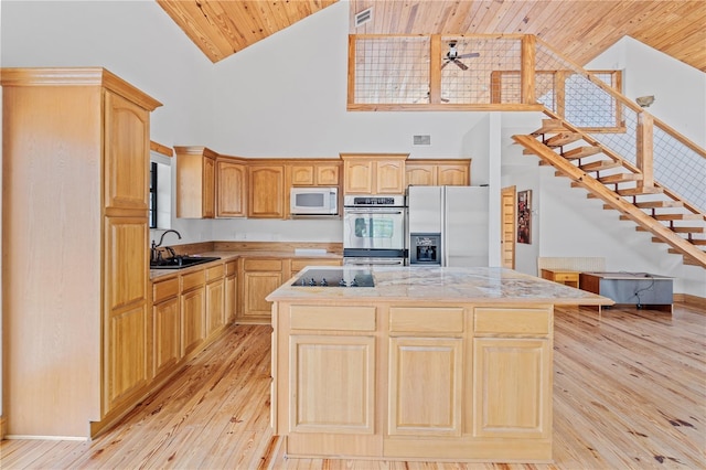 kitchen featuring a center island, high vaulted ceiling, sink, light brown cabinetry, and stainless steel appliances