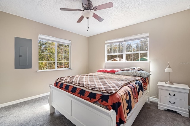 bedroom with electric panel, ceiling fan, dark carpet, and multiple windows