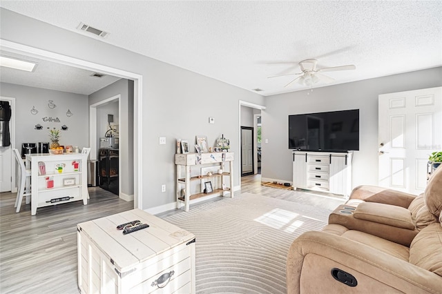 living room with ceiling fan, light hardwood / wood-style floors, and a textured ceiling