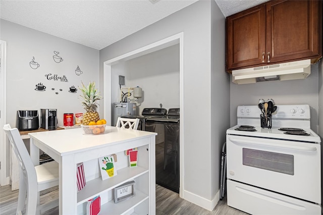 kitchen with a breakfast bar, a textured ceiling, light hardwood / wood-style flooring, white electric range, and washing machine and dryer