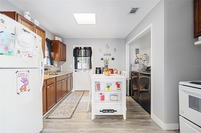 kitchen with washer and clothes dryer, light hardwood / wood-style flooring, white appliances, and sink