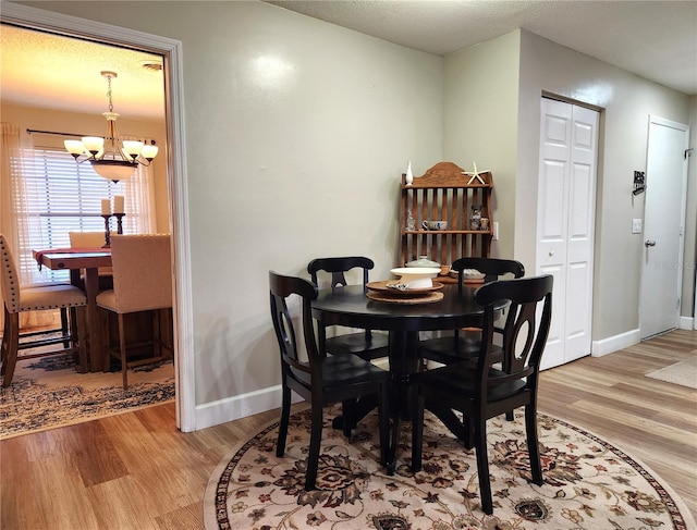 dining room with light hardwood / wood-style flooring, a textured ceiling, and an inviting chandelier