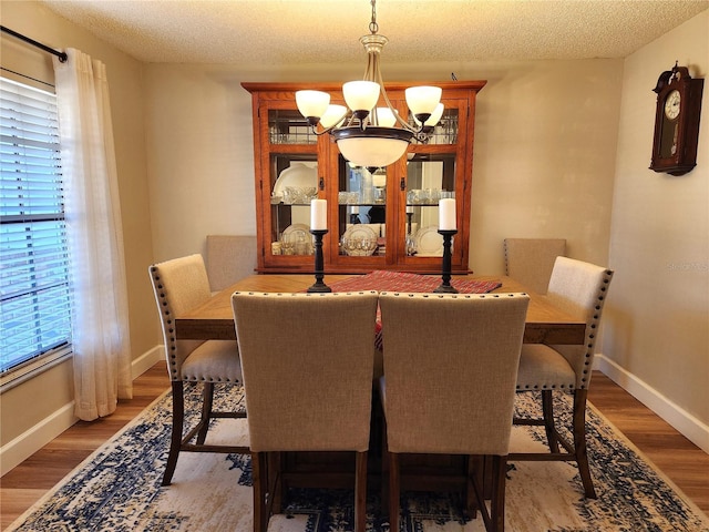 dining space with hardwood / wood-style flooring, a textured ceiling, and a chandelier